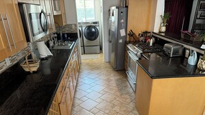 A kitchen with a central island, a washing machine, a refrigerator, and a stove. - Peaceful Covina Stay Close to LA, Disney/Work & Adventure (Covina)