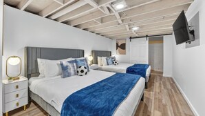 Habitación de hotel moderna con dos camas, un televisor montado en la pared y techo de madera.