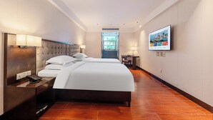 A hotel room with a large bed, bedside tables, a desk, and a television on the wall. - Shenzhen Airport Hotel Bao'an Airport  (Shenzhen)