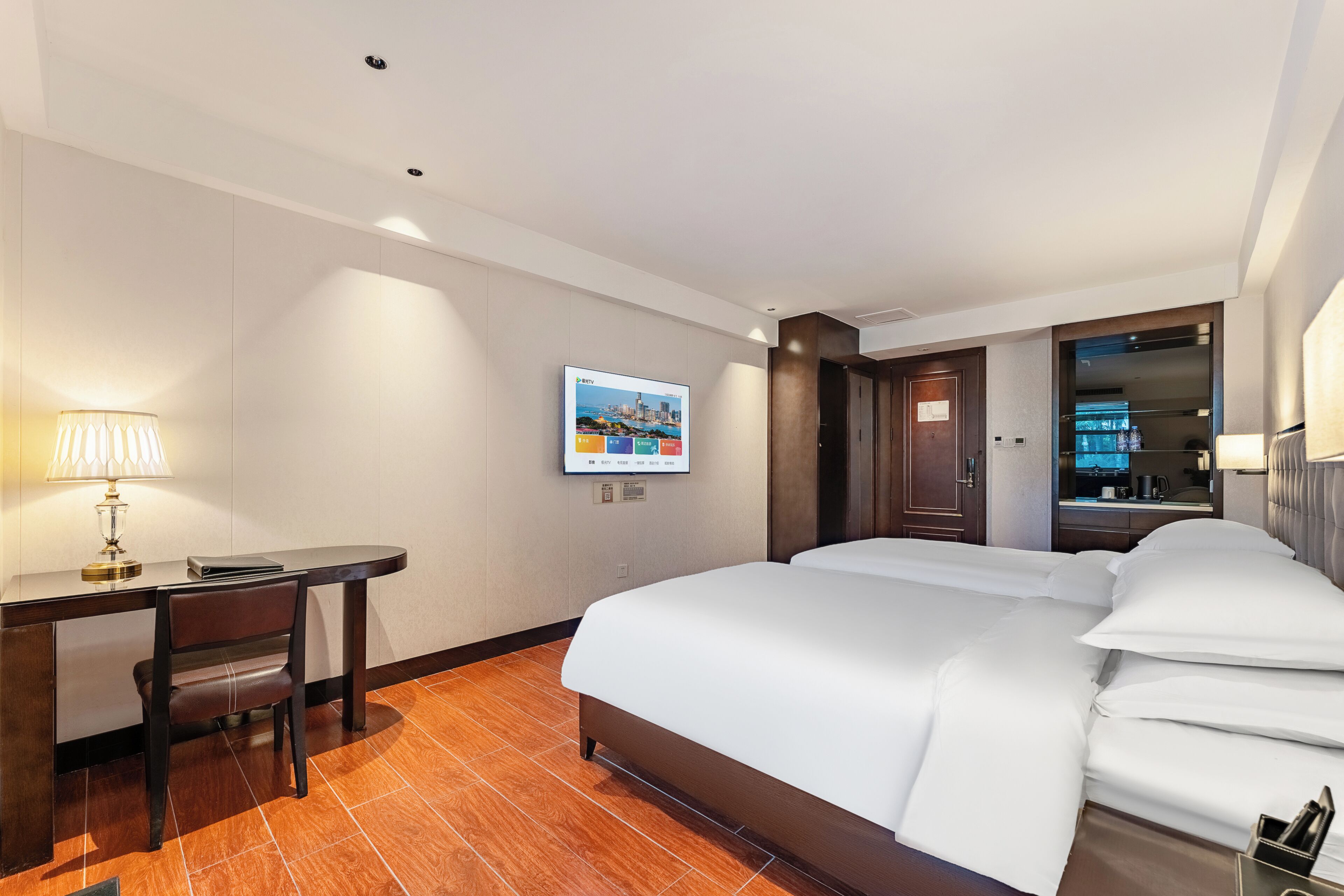 Una camera d'albergo con un letto, una scrivania, una sedia e una televisione a parete.
