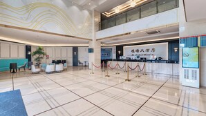 A hotel lobby with a reception desk, seating area, and a digital information board. - Shenzhen Airport Hotel Bao'an Airport  (Shenzhen)