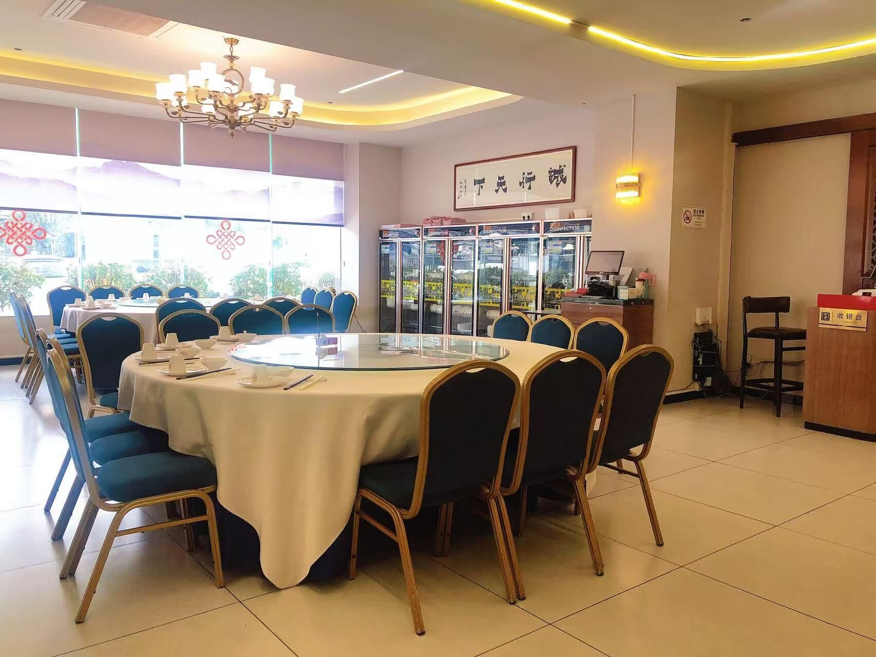 A conference room with a round table, blue chairs, and a chandelier.