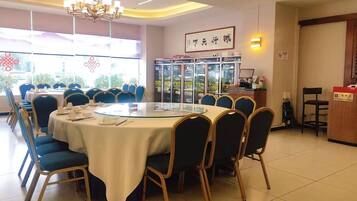 A conference room with a round table, blue chairs, and a chandelier.