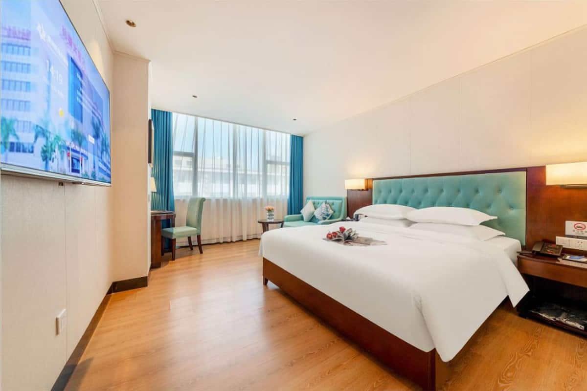 Una habitación de hotel con una cama grande, televisión, escritorio y una silla.