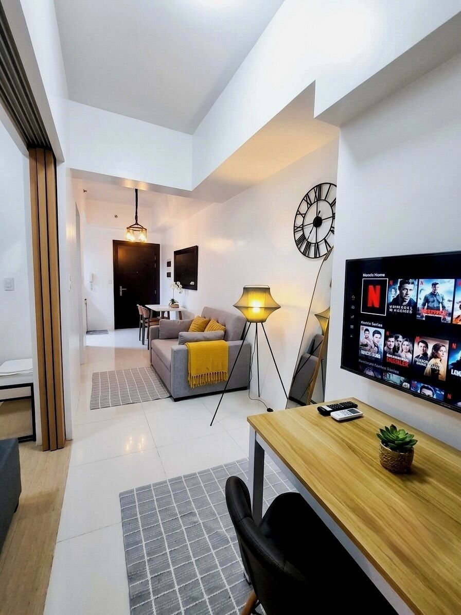 A modern living room with a flat-screen TV, a sofa, a coffee table, and a lamp.