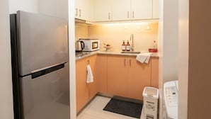 A compact kitchen with a refrigerator, microwave, sink, and a small countertop area. - Modern Central 1BR Apt - Prime City of BGC, Manila (Taguig)