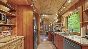 A wooden cabin kitchen with a refrigerator, stove, sink, and wooden cabinets.