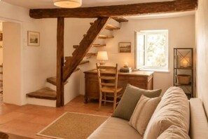 Une pièce chaleureuse avec un escalier en bois, un canapé, un bureau et une lampe.