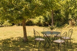 A round metal table with four chairs, surrounded by grass and trees. - A farmhouse in the heart of nature, with panoramic views and absolute peace and quiet. (Sault)
