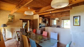 A dining area with a glass table, chairs, and a wooden ceiling.