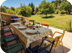 An outdoor dining area with a stone wall, a grill, and a table set for a meal.