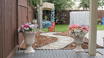 Ein Patio mit zwei großen Blumentöpfen, einem Holzzaun und einer Spielanlage im Hintergrund.