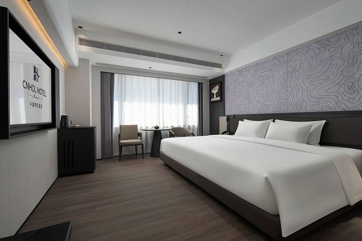 Une chambre d’hôtel moderne, dotée d’un grand lit, d’un bureau et d’une chaise.
