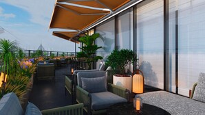 Une terrasse sur le toit, aménagée avec des espaces de détente en plein air, des plantes en pot et offrant une vue sur le panorama urbain.