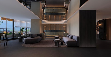 A modern lounge area with a curved seating arrangement, a central coffee table, and a view of the outdoors through large windows.