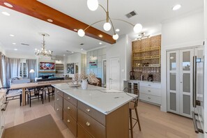 A modern kitchen with a central island, wooden cabinets, and a decorative backsplash. - Modern Zilker Retreat | Downtown Views + Walk to ACL & Barton Springs (Austin)