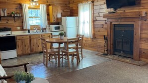 A wooden cabin interior with a dining area, kitchen, and fireplace. - The Hawthorn on Table Rock Lake, 2 Bed/2 Bath Log Cabin, Pool, Hot Tub & Dock (Shell Knob)