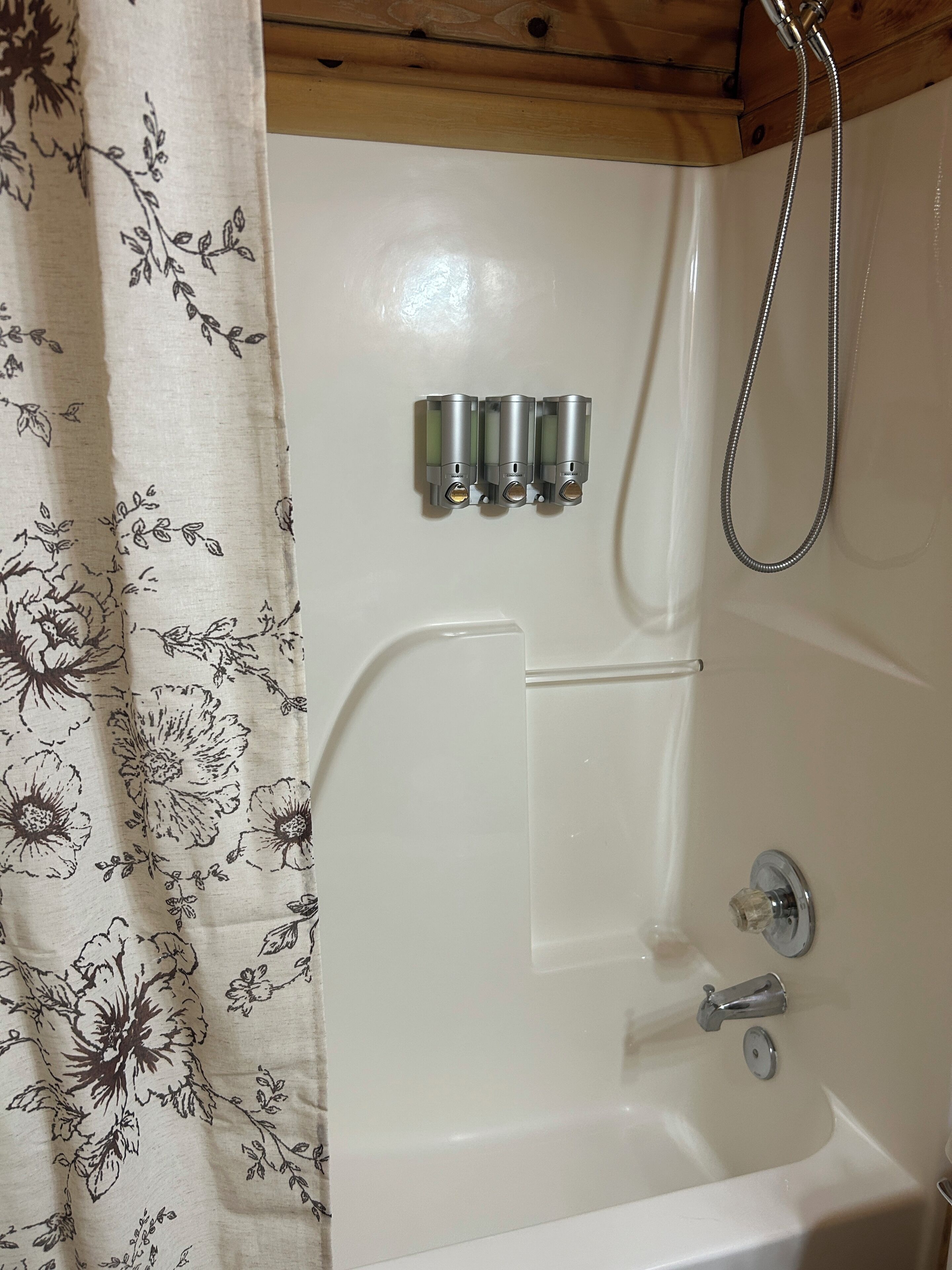 A bathroom with a bathtub, a shower, and a curtain with a floral pattern.