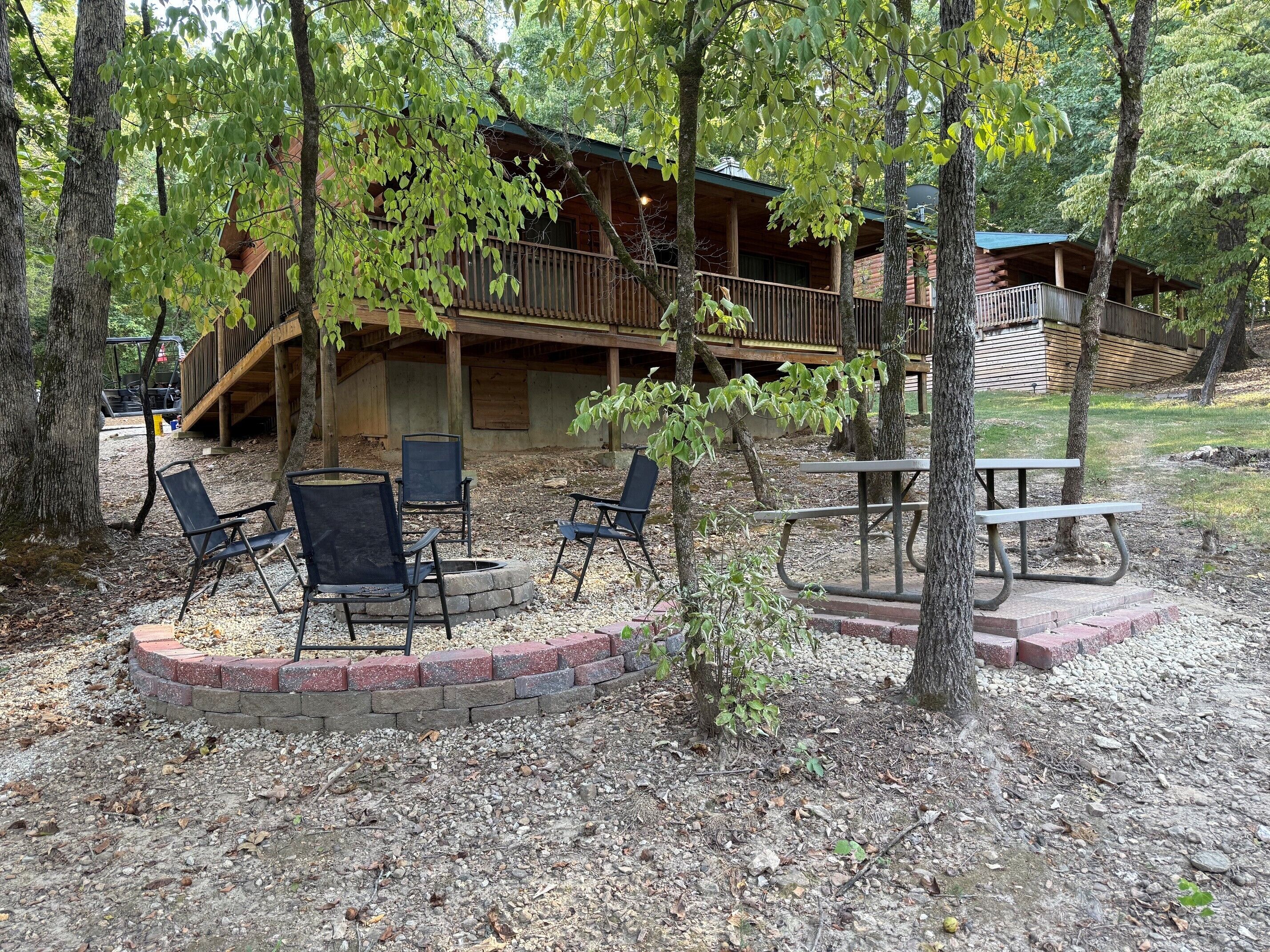 Un chalet rustique doté d’une véranda, d’un espace extérieur aménagé pour s’asseoir et d’un foyer.