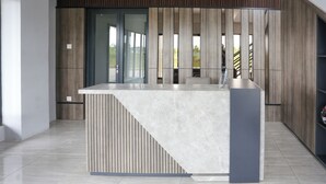 Un comptoir d’accueil moderne, doté d’un plateau en marbre et de panneaux en bois.
