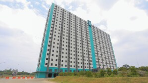 Un immeuble de grande hauteur doté d’une architecture moderne, caractérisé par une palette de couleurs dominante allant du turquoise au blanc.