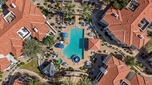 Vista aerea di un resort con piscina centrale, circondata da zone relax e passerelle coperte.