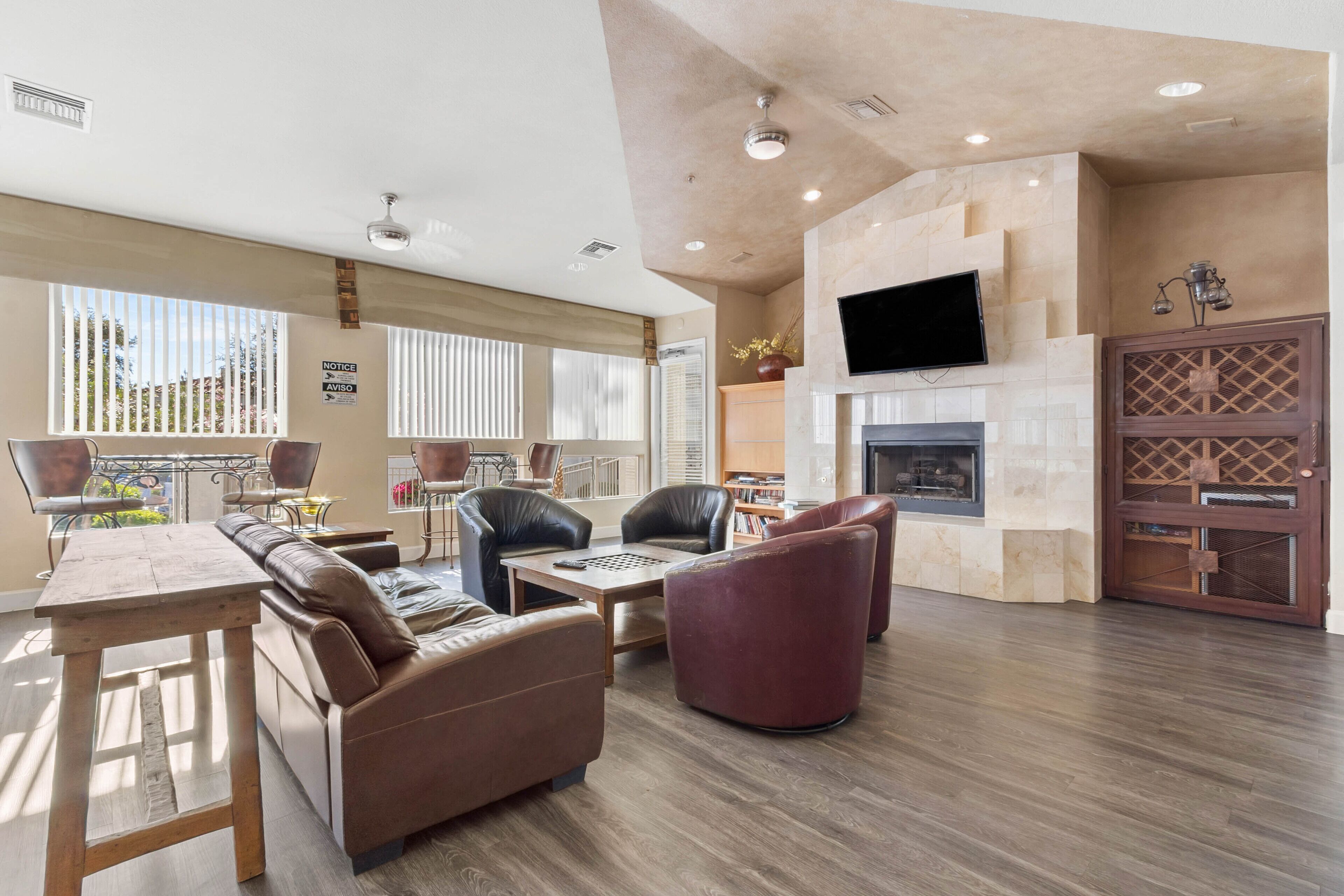 A spacious living area with a fireplace, leather sofas, a dining table, and a TV mounted on the wall.