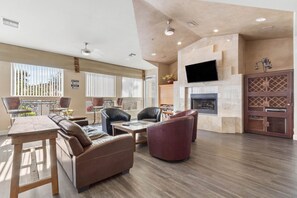 A spacious living area with a fireplace, leather sofas, a dining table, and a TV mounted on the wall. - Scottsdale Somerset Hideaway with Pool and Hot Tub - near Mayo (Scottsdale)