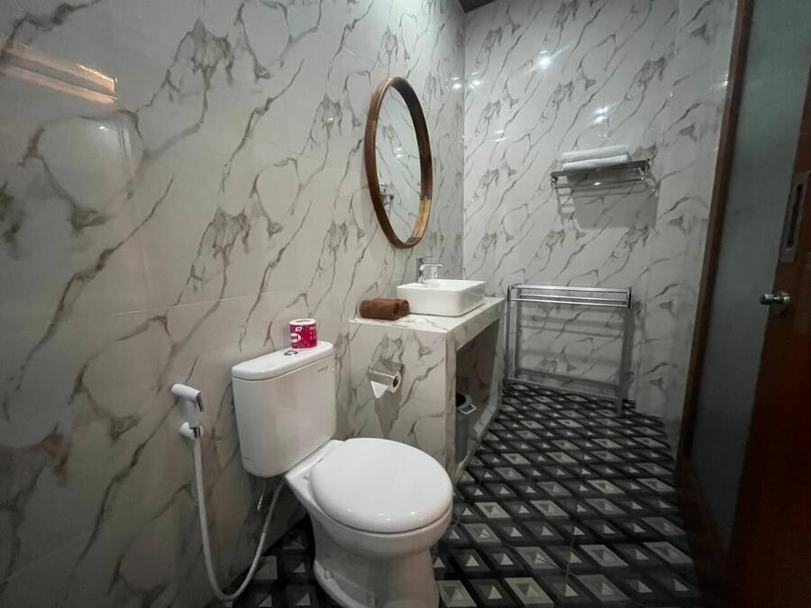 A bathroom with a toilet, sink, and mirror.