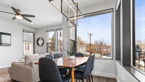 Un comedor moderno con una mesa y sillas de madera, ventanas amplias que ofrecen vistas al exterior y un ventilador de techo.