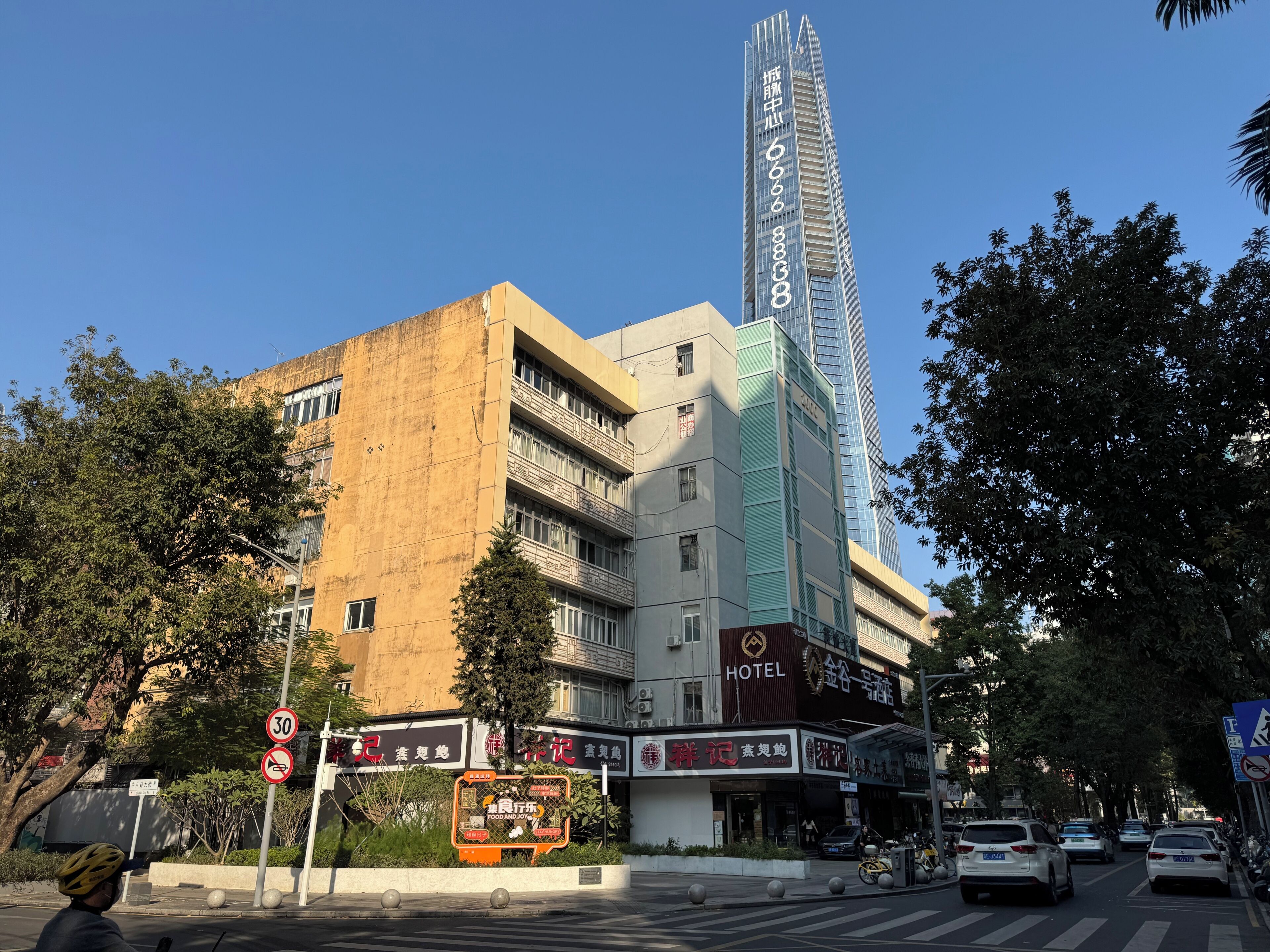 Hotel com design moderno, uma estrutura vertical imponente e uma placa indicando limite de velocidade de 30 km/h.