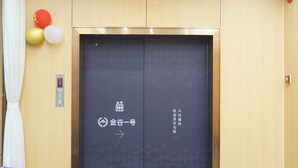 Un'area reception di un hotel, con la scrivania, un display digitale e l'ingresso della reception con segnaletica direzionale.