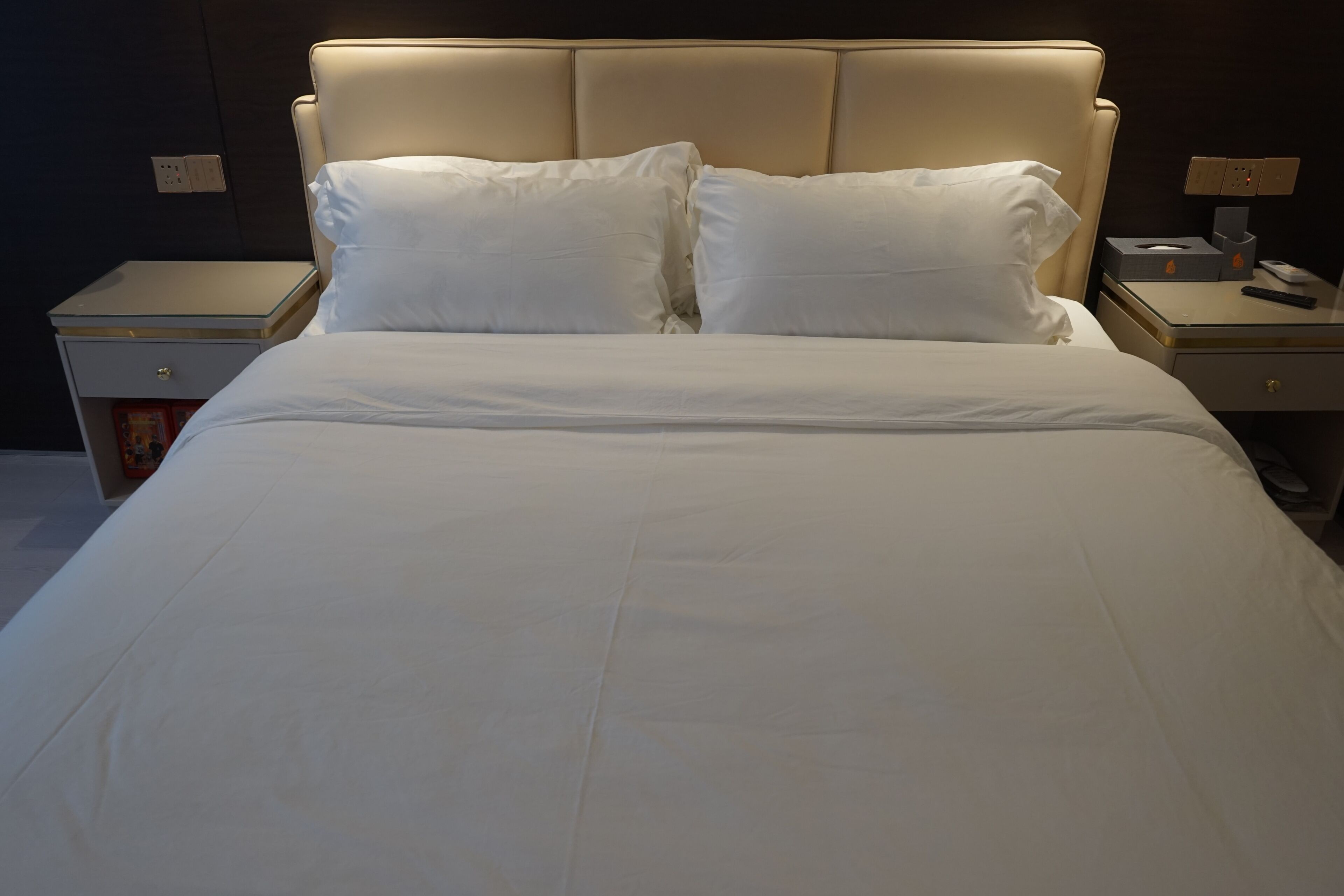 A bed with white linens, a headboard, and bedside tables with lamps and a tissue box.