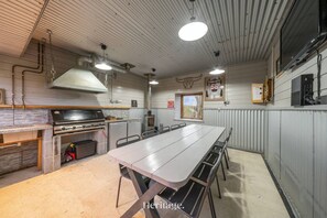 A compact kitchen with a large table and chairs, a built-in oven, and a hanging light fixture. - The Steading Family Friendly Getaway (Peterhead)