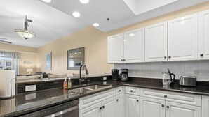 A modern kitchen with white cabinets, a black countertop, and stainless steel appliances including an LG dishwasher and a coffee maker. - Welcome to Oceanwalk 15-505! (New Smyrna Beach)