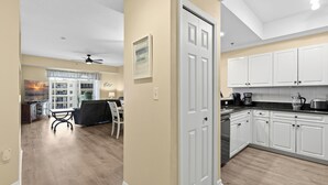 A modern kitchen with white cabinets and a dining area with a table and chairs. - Welcome to Oceanwalk 15-505! (New Smyrna Beach)