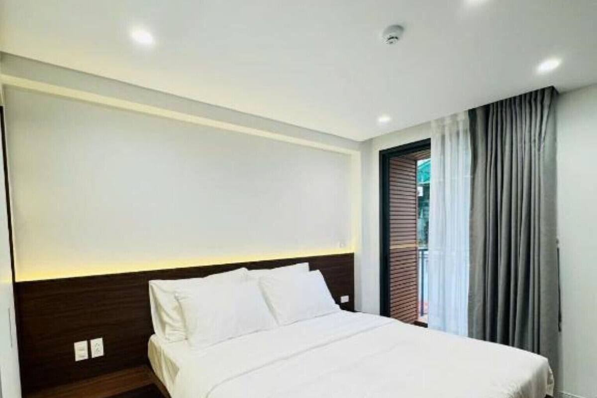 Una habitación de hotel moderna con una cama grande, cabecera con iluminación integrada, ventana con cortinas y suelo de madera.