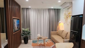 Ein modernes Wohnzimmer mit einer Couch, einem kleinen runden Tisch, einer Zimmerpflanze und einem Fernseher.