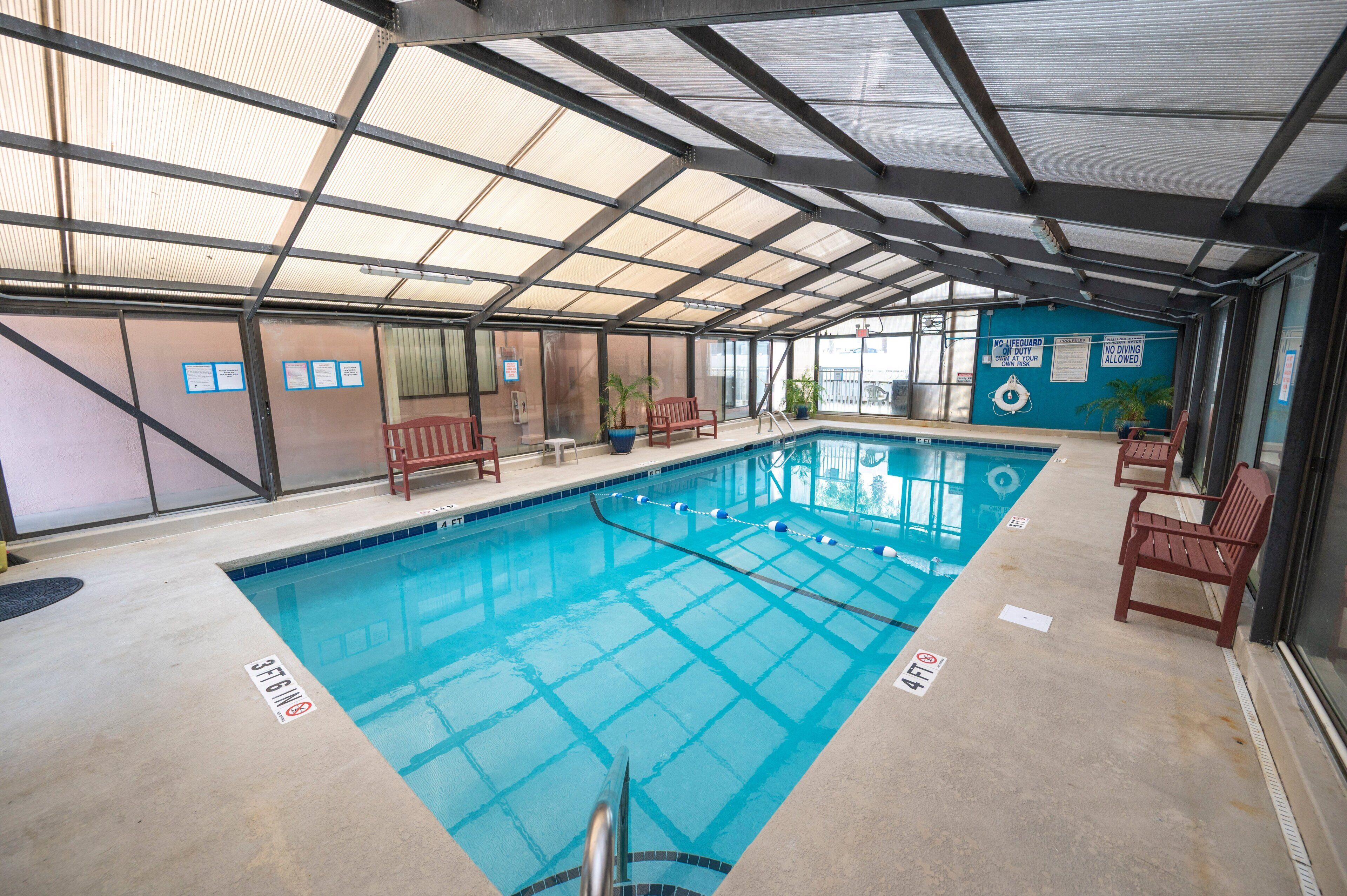 An indoor swimming pool with clear water, marked lanes, and safety signs.