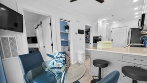 Una cocina moderna con gabinetes blancos, un refrigerador negro y una isla de vidrio con taburetes de bar.