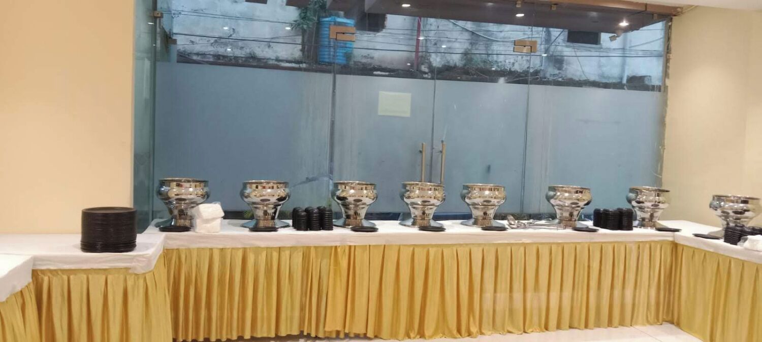 A banquet table with multiple trophies, a white tablecloth, and a gold drape.