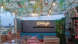 Un restaurante con letrero de neón, plantas colgantes y mobiliario de madera.