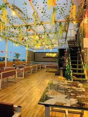 An indoor space with wooden benches, a glass table, and hanging plants. - Hotel Harriot Bhopal (Bhopal)