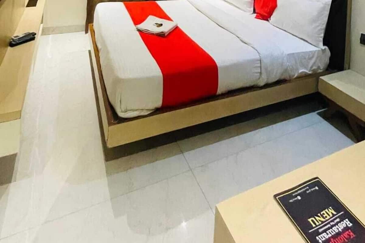 A hotel room with a bed, a nightstand, a TV, and a ceiling fan.