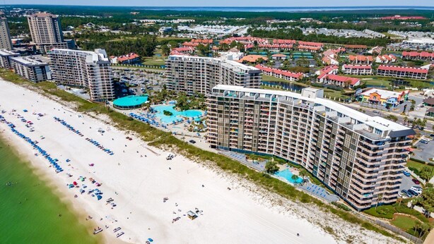 Ein Küstenresort mit mehreren Hochhäusern, einem Sandstrand und einem großen Schwimmbad.