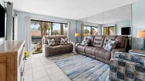 Ein modernes Wohnzimmer mit einem braunen Ledersofa, einem gemusterten Sessel und einem blau gestreiften Teppich.