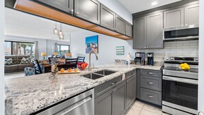 Una cocina moderna con encimeras de granito, electrodomésticos de acero inoxidable y muebles oscuros.
