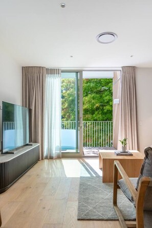 Una sala de estar moderna con un televisor de pantalla plana, una mesa de centro de madera y un sofá.