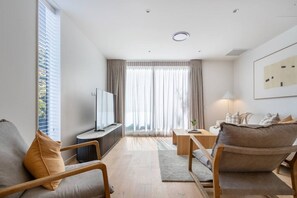 Ein modernes Wohnzimmer mit Flachbildfernseher, Sofa, Couchtisch und Lampe.