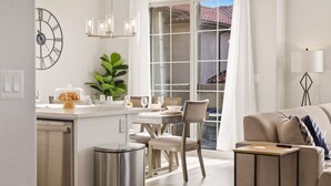 Uma cozinha moderna com área de jantar, uma janela grande com cortinas e uma sala de estar aconchegante com sofá e luminária.